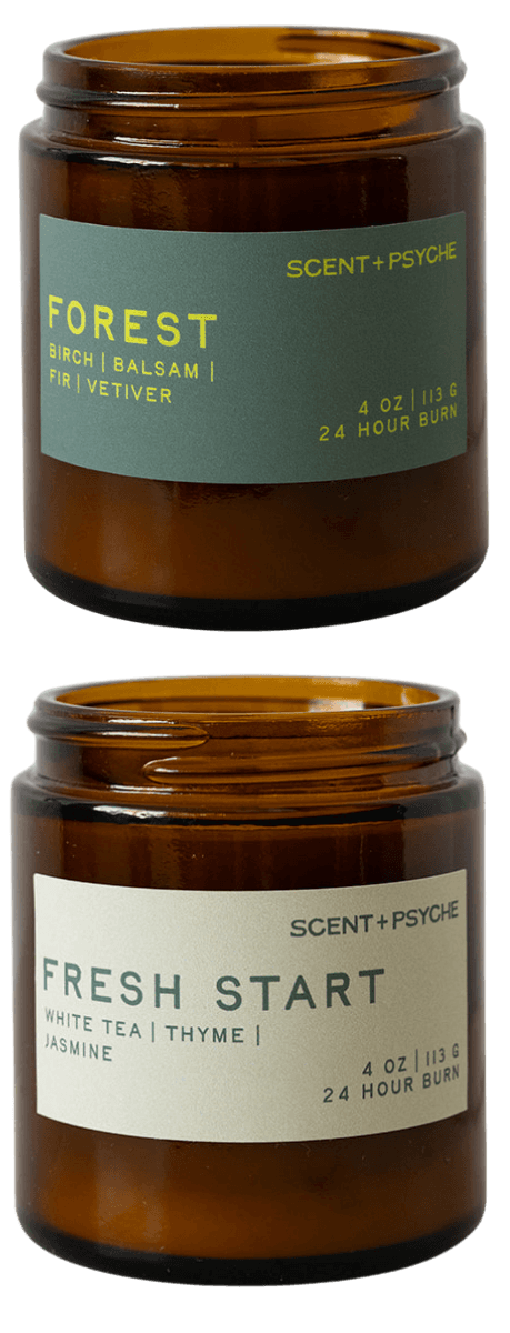 Two amber glass jar candles on a white background, one labeled Forest and one labeled Fresh Start, from Scent + Psycho.