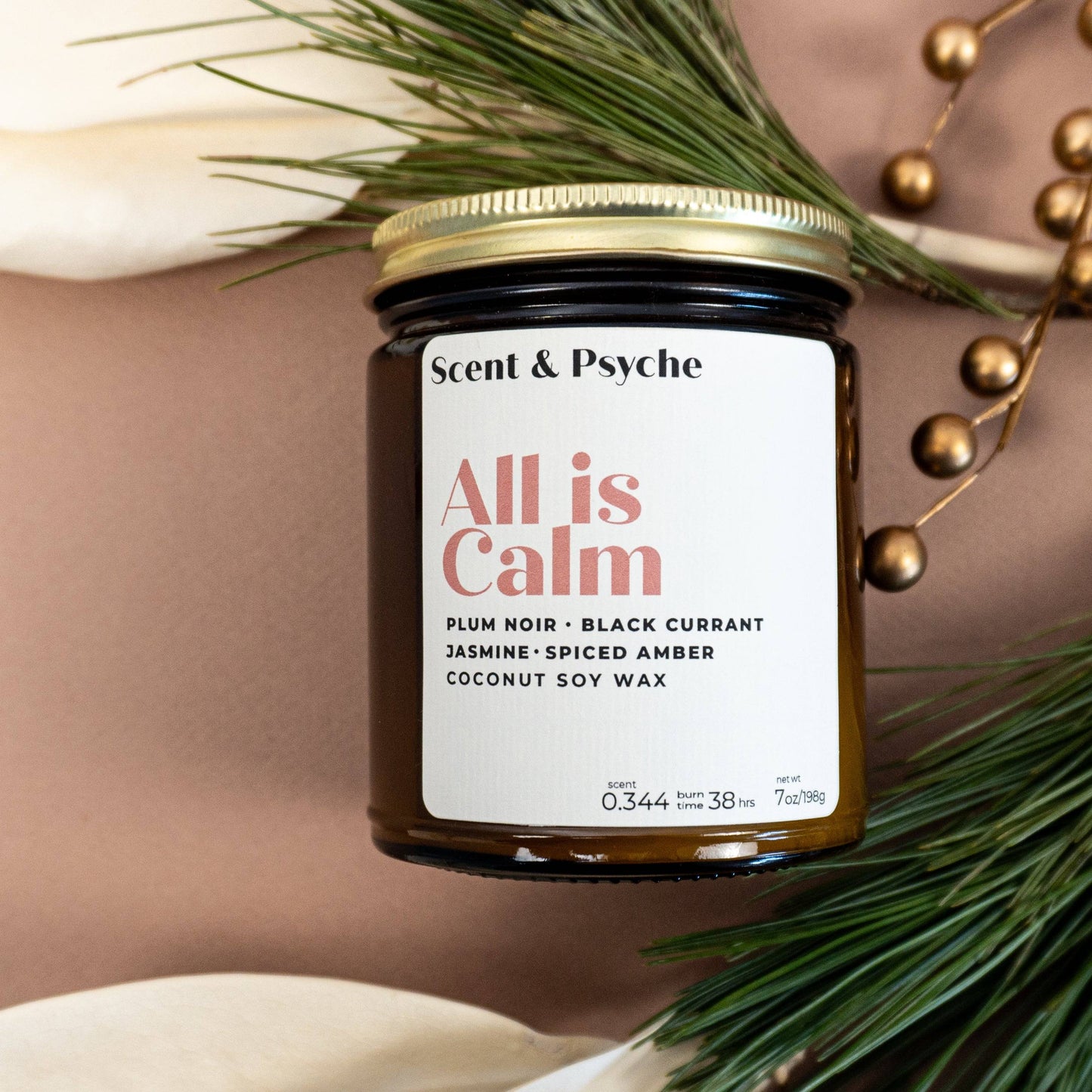 All is Calm Scented Candle in 7oz amber jar with gold lid, featuring notes of plum noir, black currant, jasmine, and spiced amber. Ideal for holiday home decor.