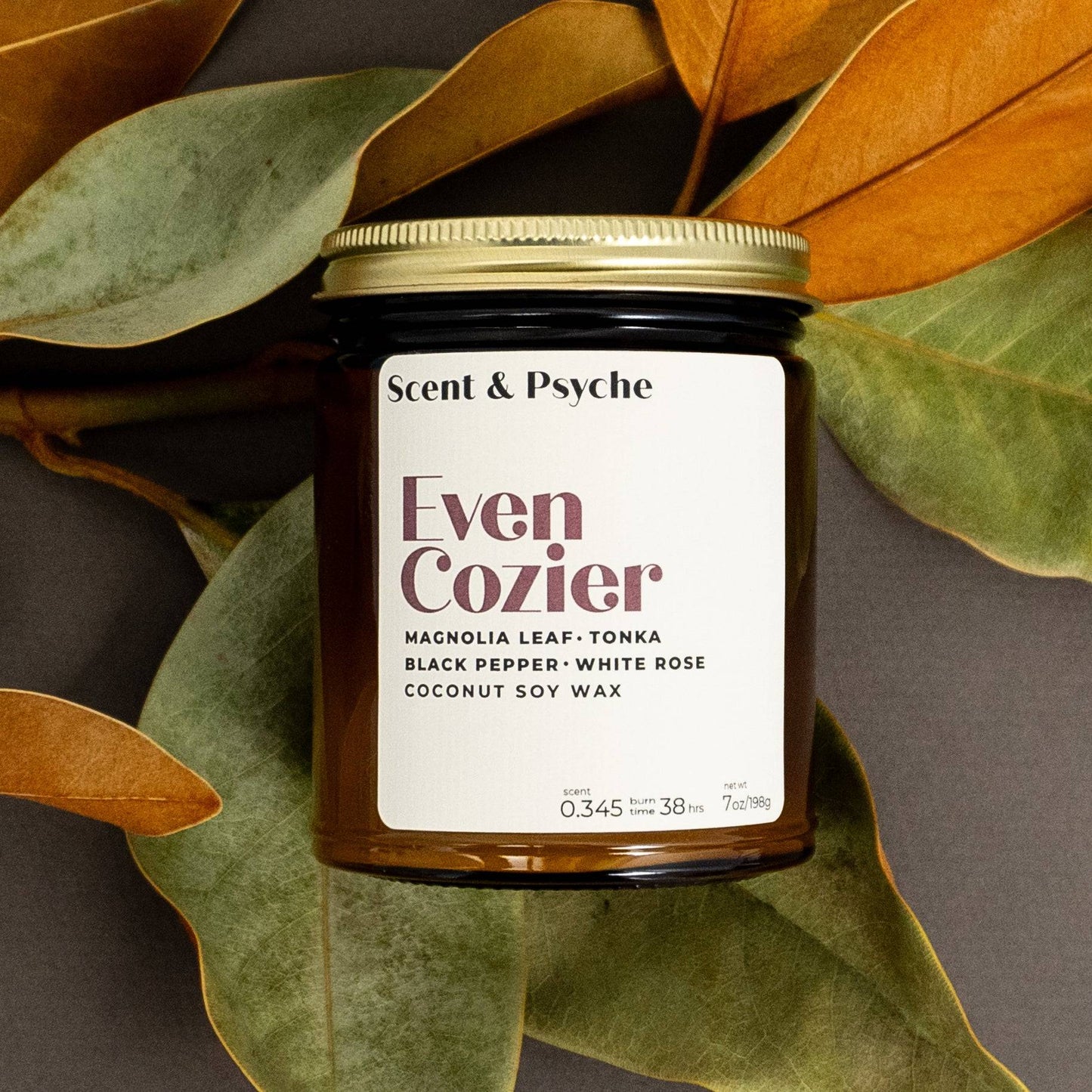 Scented Candle 7oz - Even Cozier Wood Wick Candle in amber jar with magnolia leaves, featuring clean-burning coconut soy wax and phthalate-free scent.
