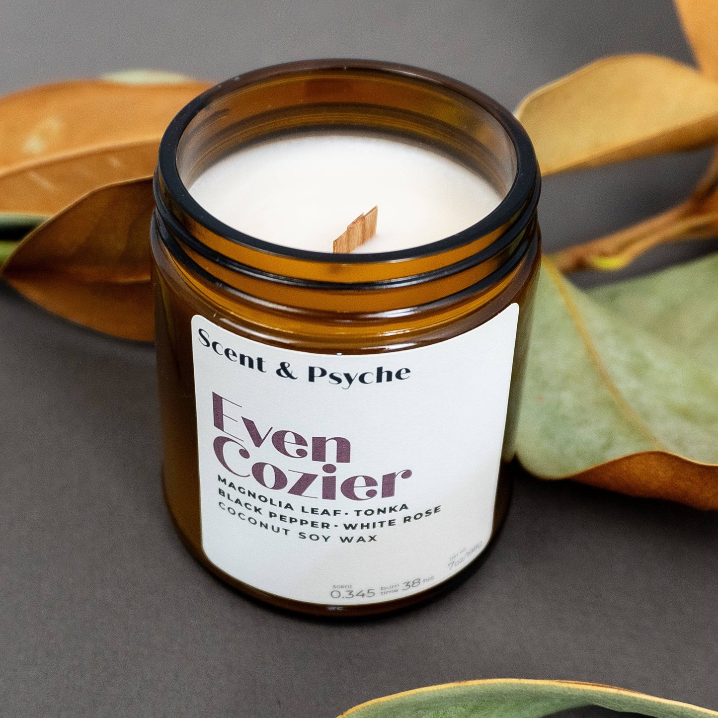 Even Cozier 7oz scented candle with wood wick in amber jar, showcasing creamy coconut soy wax and elegant label for home fragrance decor.