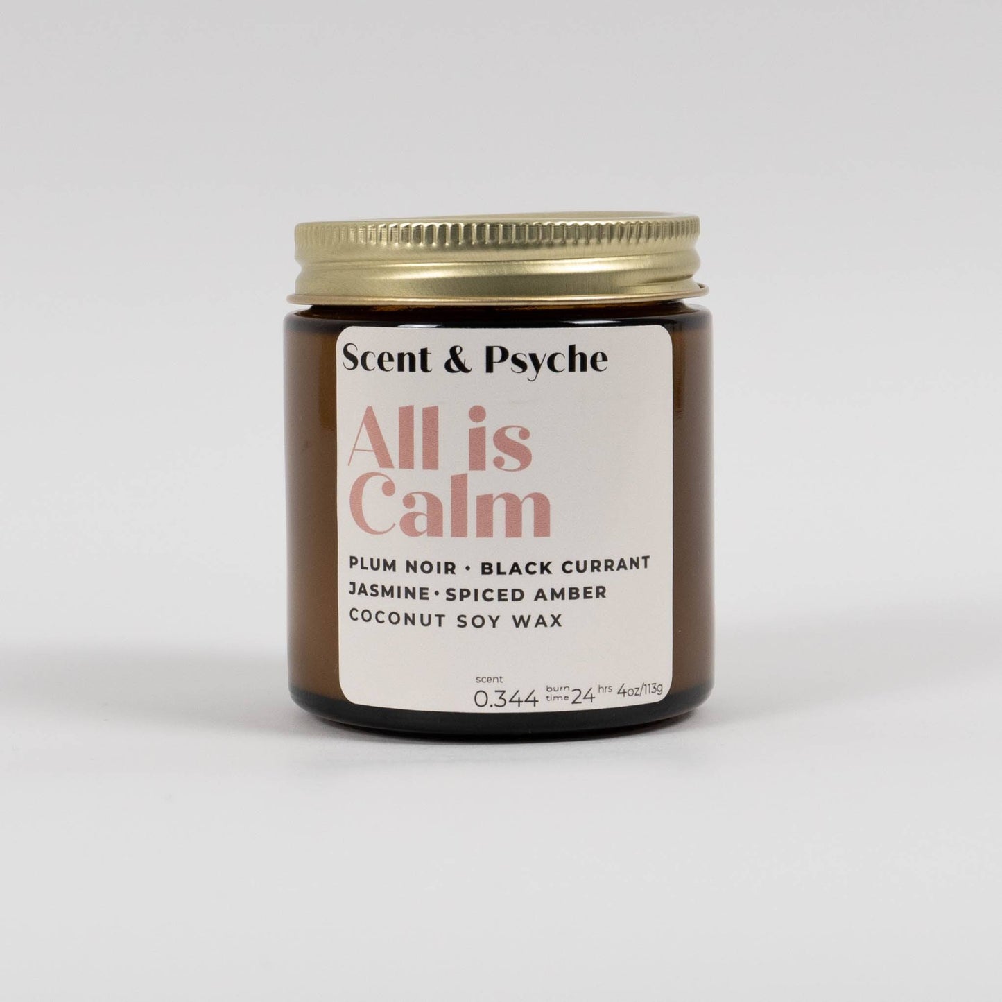All is Calm Scented Candle in 4oz amber jar with gold lid, labeled with plum noir, black currant, and spiced amber scent notes.