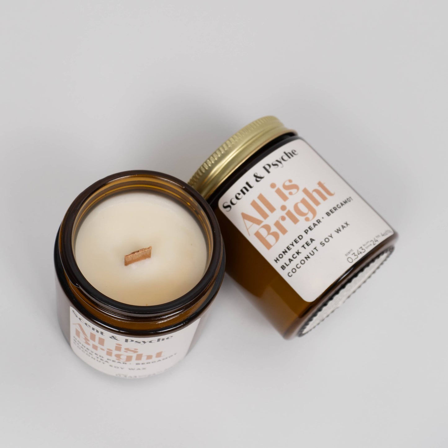 Open and closed All is Bright Scented Candle in 4oz amber jars with coconut soy wax and wooden wick, ideal for holiday home decor.