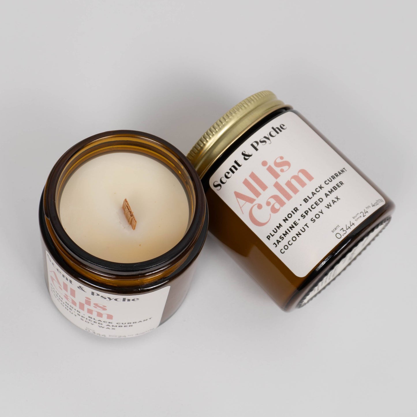 All is Calm Scented Candle shown open and closed, featuring coconut soy wax and wooden wick in amber jars, perfect for holiday gifting.