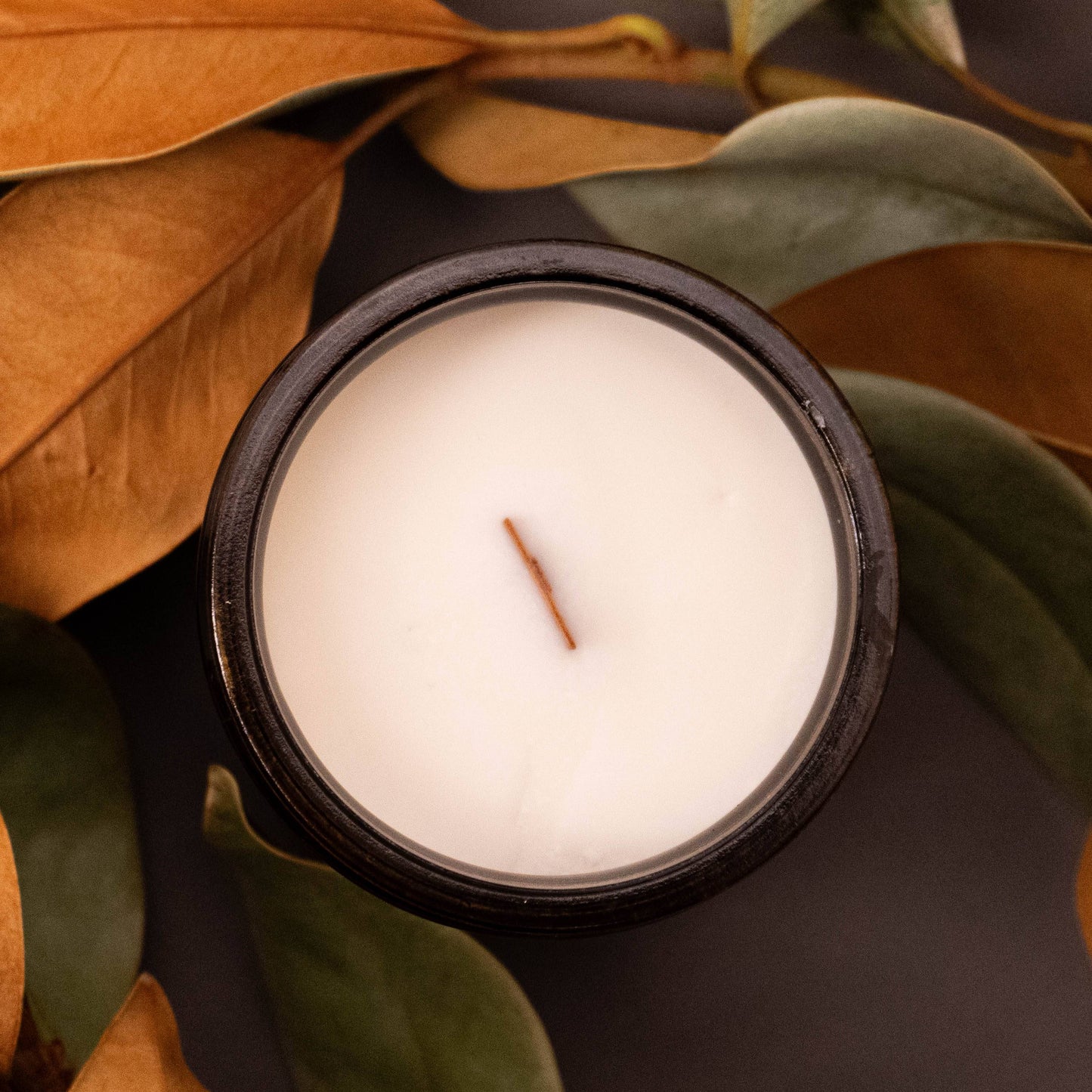 Scented Candle 12oz - Even Cozier Wood Wick Candle in amber jar with creamy coconut soy wax, surrounded by autumn leaves for fall decor appeal.