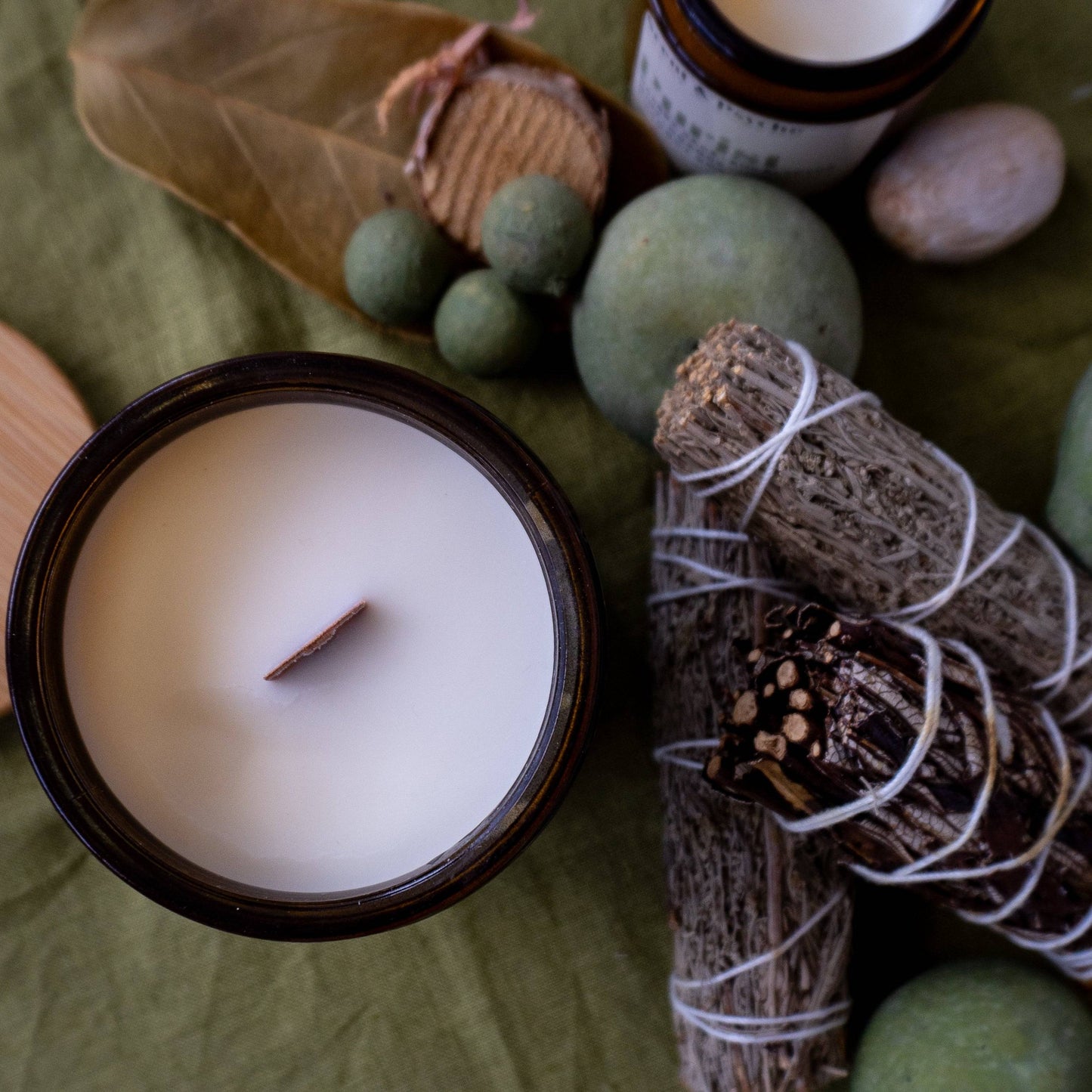 Top view of the Purist Scented Candle in a 12oz amber jar, showcasing a wooden wick and smooth coconut soy wax. Surrounded by natural elements for a rustic aesthetic.