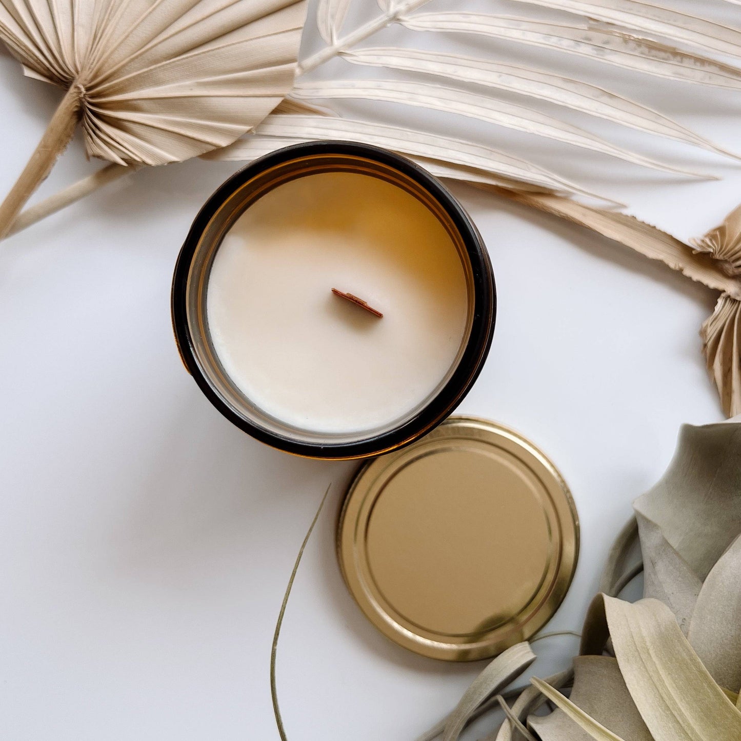Top view of the Casita Scented Candle in a 7oz amber jar, showcasing a wooden wick and smooth coconut soy wax. Includes a gold lid for an elegant touch.