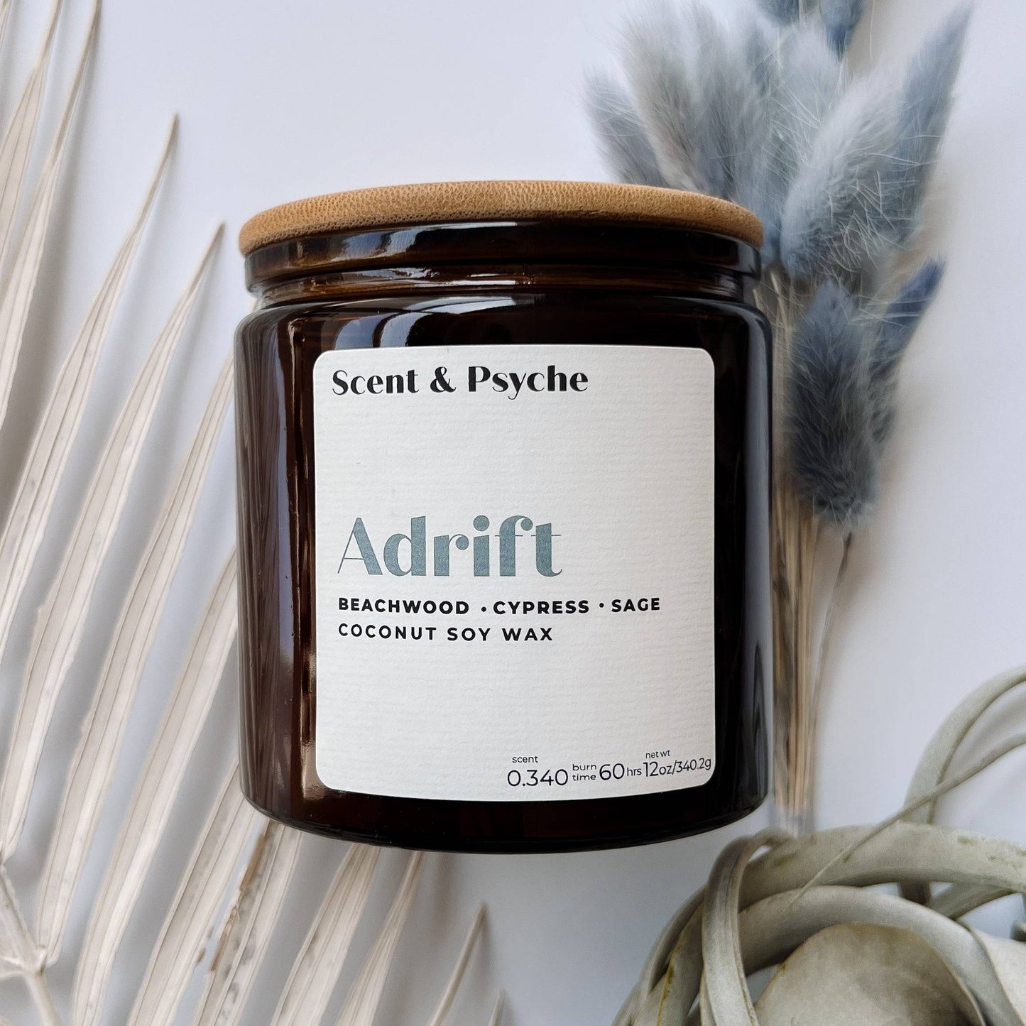 Adrift Scented Candle in a 12oz amber jar with a wooden lid, featuring beachwood, cypress, and sage fragrance. Aesthetic home decor piece.
