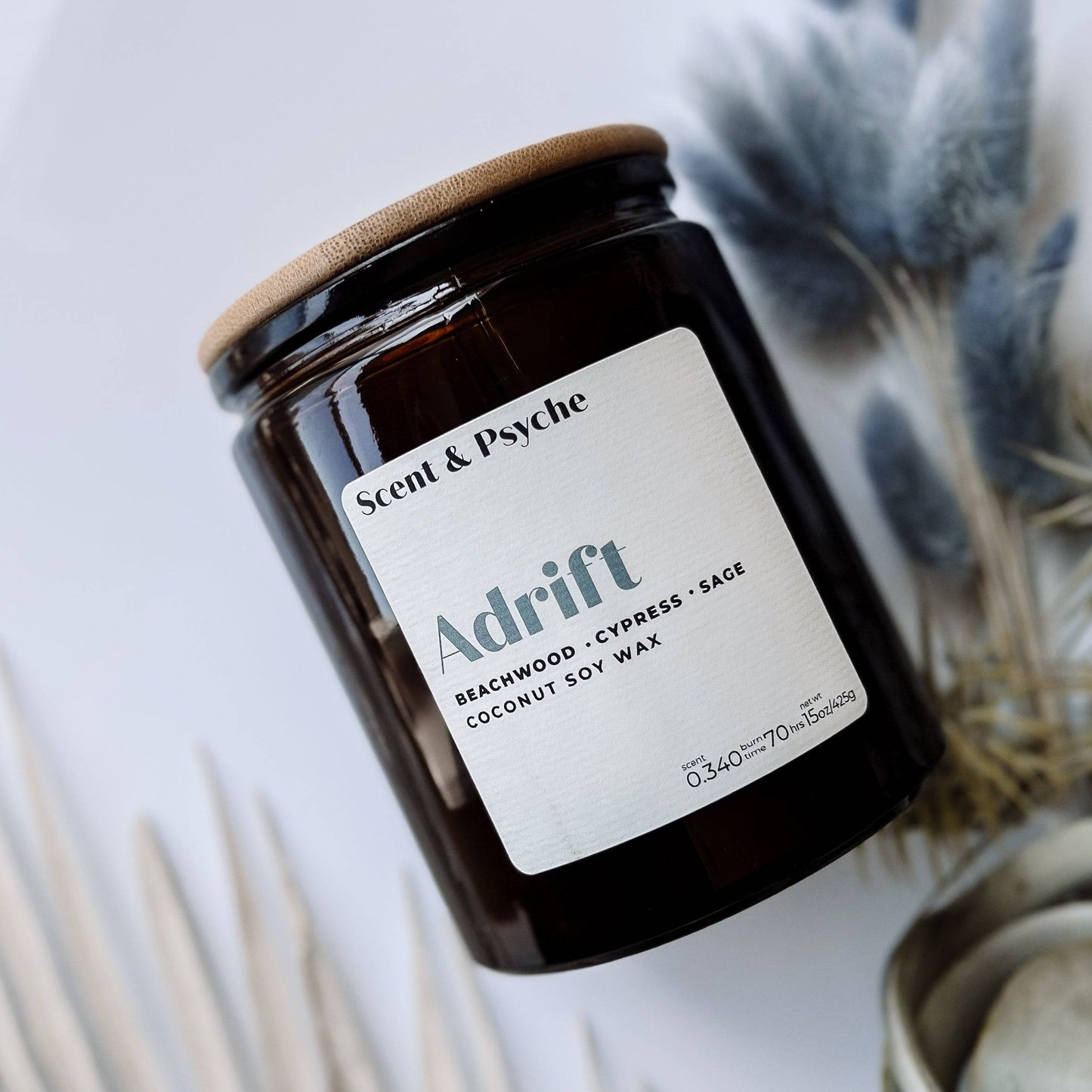 Adrift Scented Candle - 15oz in an amber glass jar with a wooden lid. Features beachwood, cypress, and sage fragrance, perfect for summer ambiance.