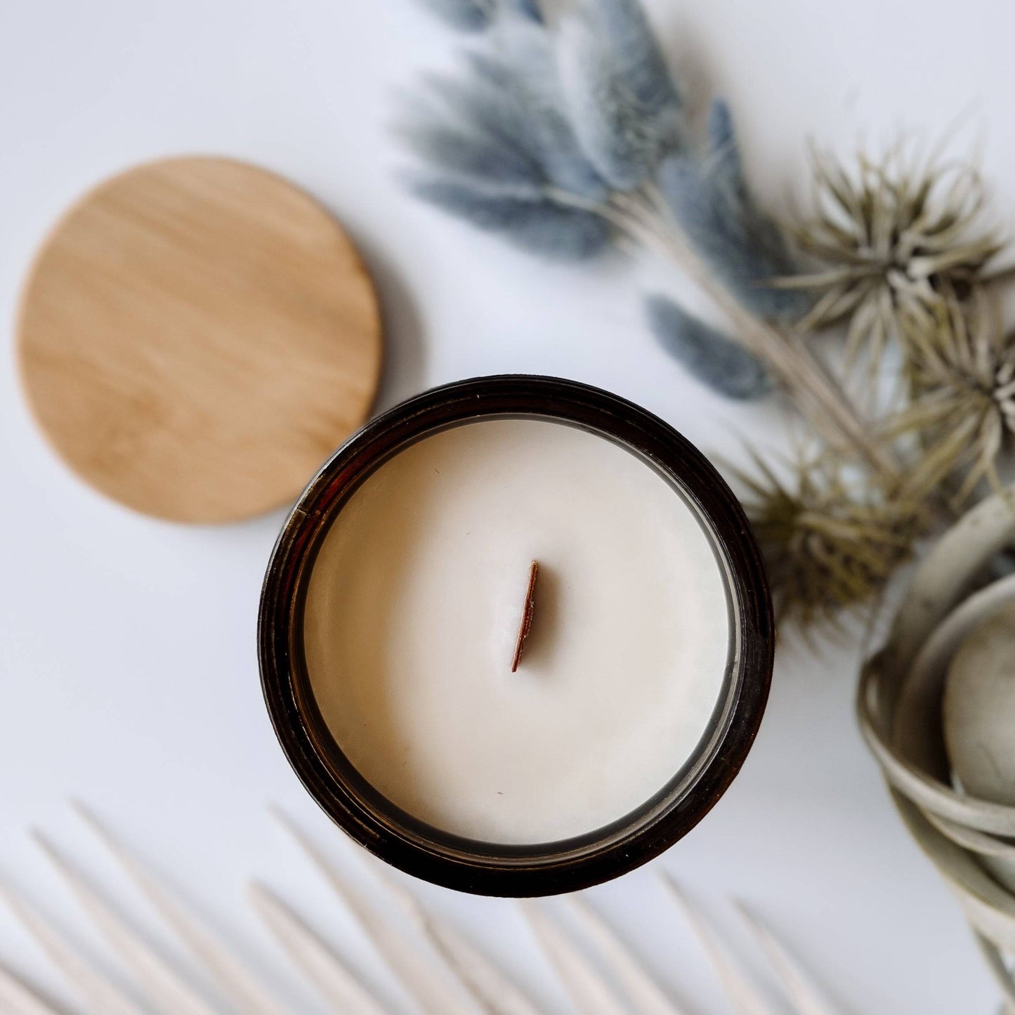 Top view of Adrift Scented Candle - 15oz with a wooden wick in a coconut soy wax blend. Comes in an amber jar with a natural wood lid for a cozy feel.