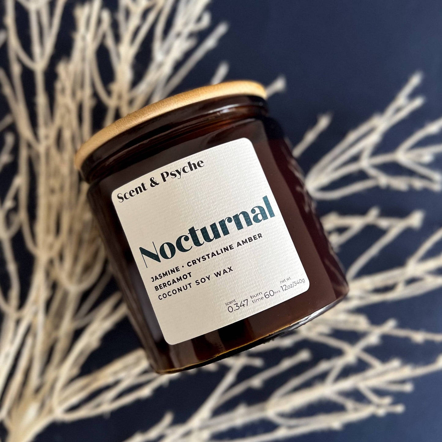 Nocturnal Scented Candle in a 12oz amber jar with a wooden lid, featuring jasmine, crystalline amber, and bergamot notes. Elegant home fragrance decor.