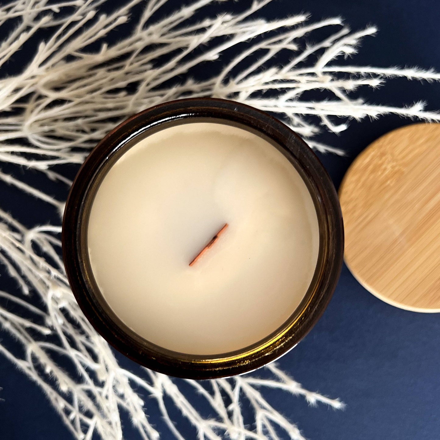 Top view of Nocturnal Scented Candle - 15oz, showcasing a smooth coconut soy wax surface with a wooden wick. Comes with a bamboo lid for a natural touch.