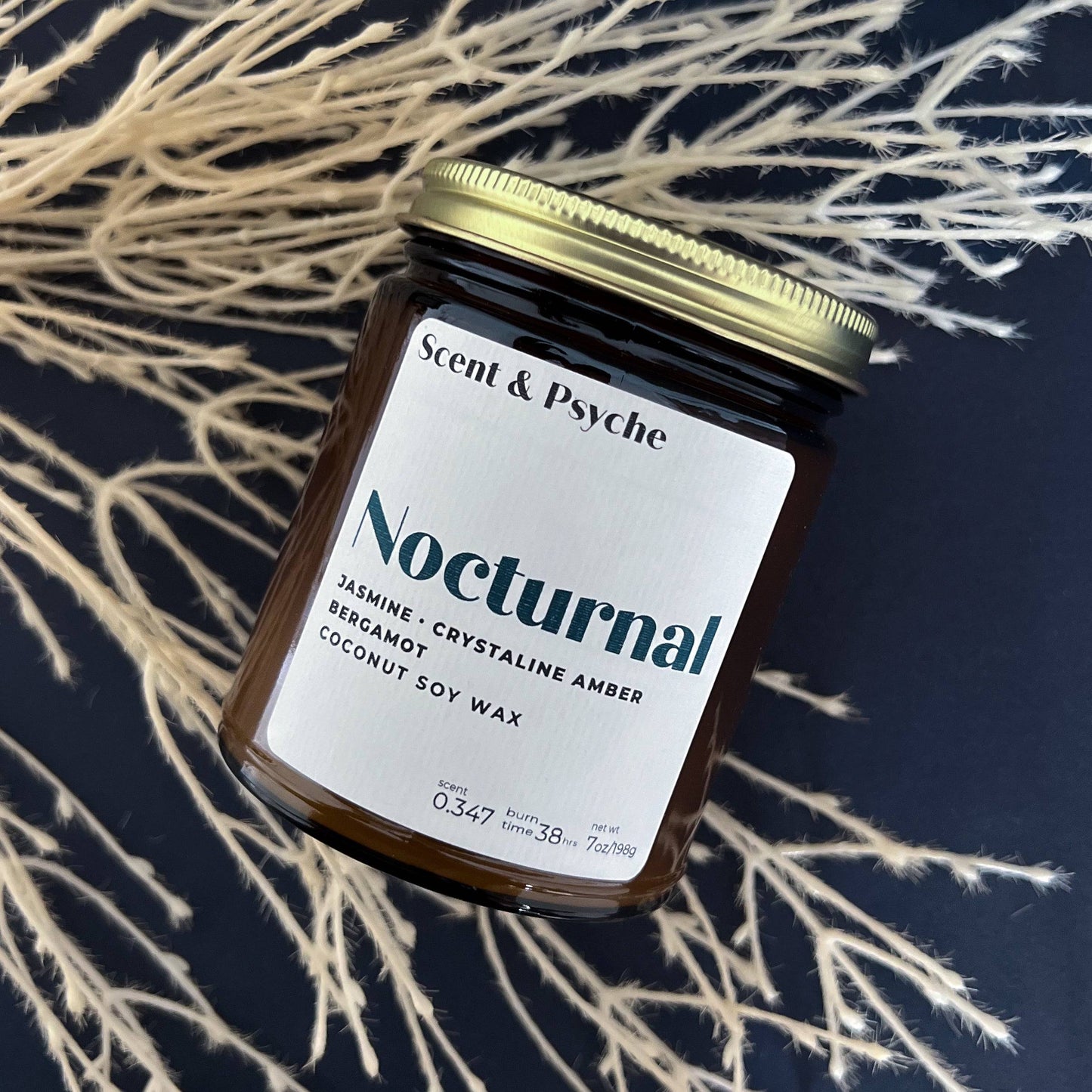 Nocturnal Scented Candle in a 7oz amber jar with a gold lid, featuring jasmine, crystalline amber, and bergamot scents. Hand-poured coconut soy wax for a long-lasting burn.
