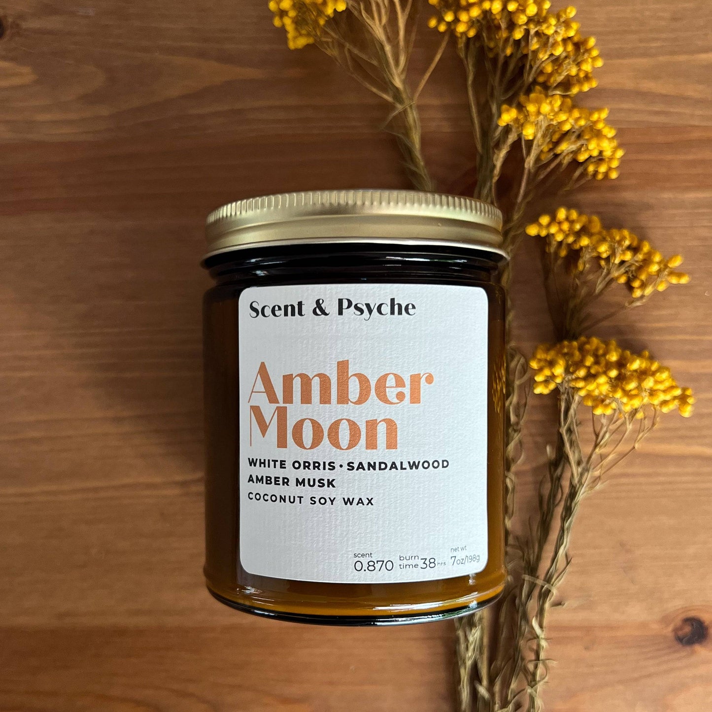 Amber Moon Scented Candle in a 7oz amber jar with a gold lid, featuring notes of white orris, sandalwood, and amber musk. Perfect for home fragrance and cozy ambiance.