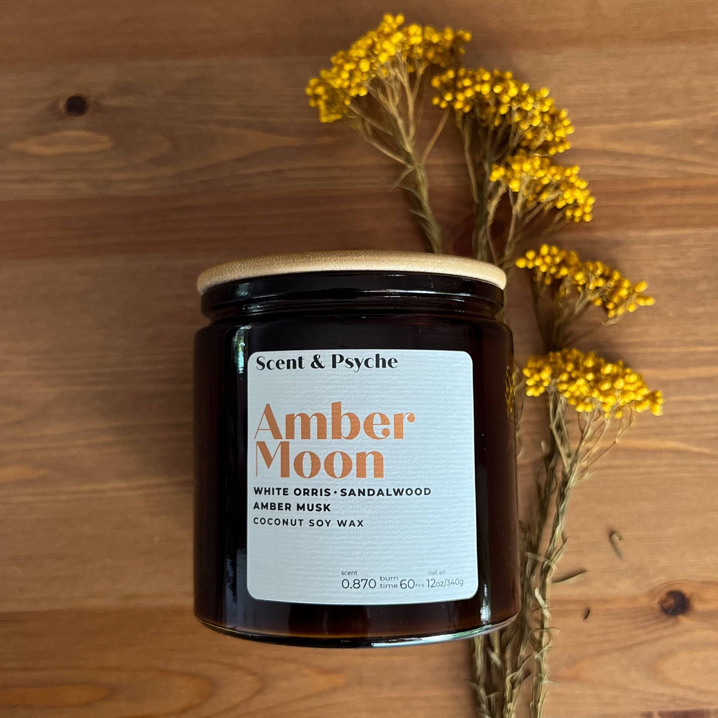 Amber Moon scented candle in a 12oz amber jar with a bamboo lid. Features notes of white orris, sandalwood, and amber musk, perfect for fall decor.