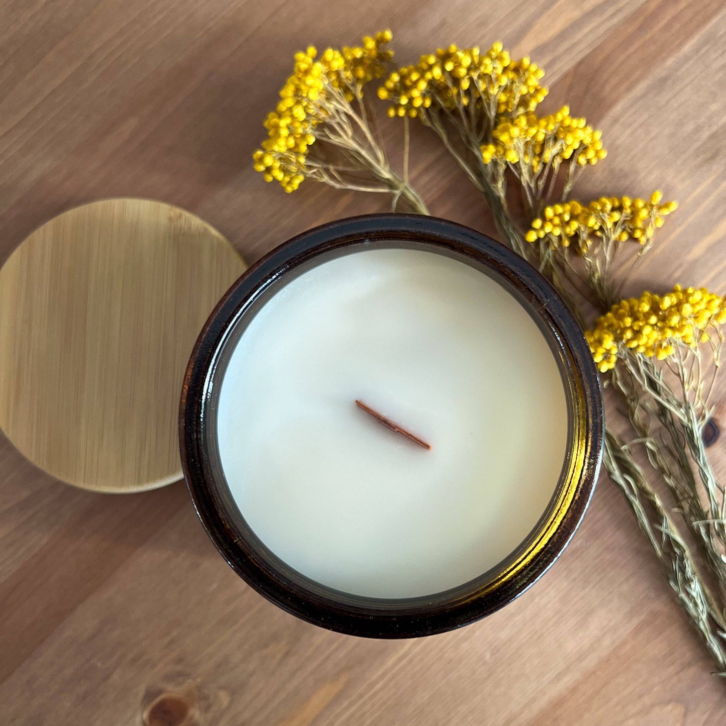 Top view of Amber Moon scented candle in a 12oz amber jar, showcasing a wooden wick and creamy coconut soy wax. Ideal for cozy home ambiance.