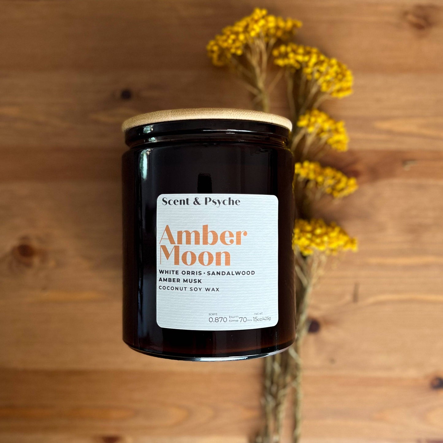 Amber Moon Scented Candle in a 15oz amber jar with a wooden lid, featuring notes of white orris, sandalwood, and amber musk. Perfect for fall home decor.