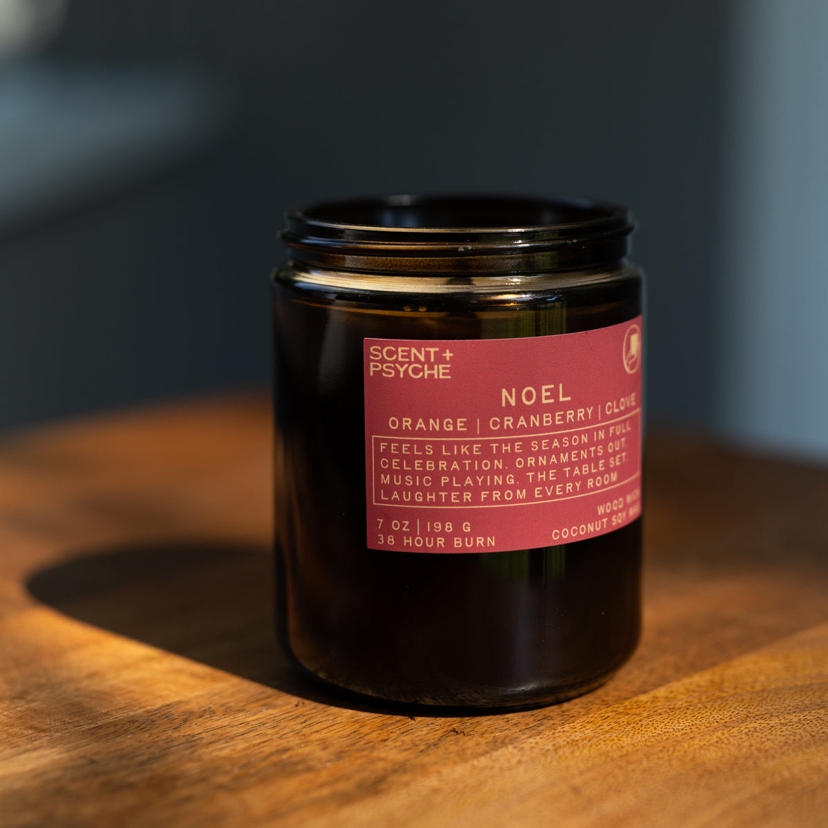 Noel wood wick candle on a wooden tabletop in warm natural light