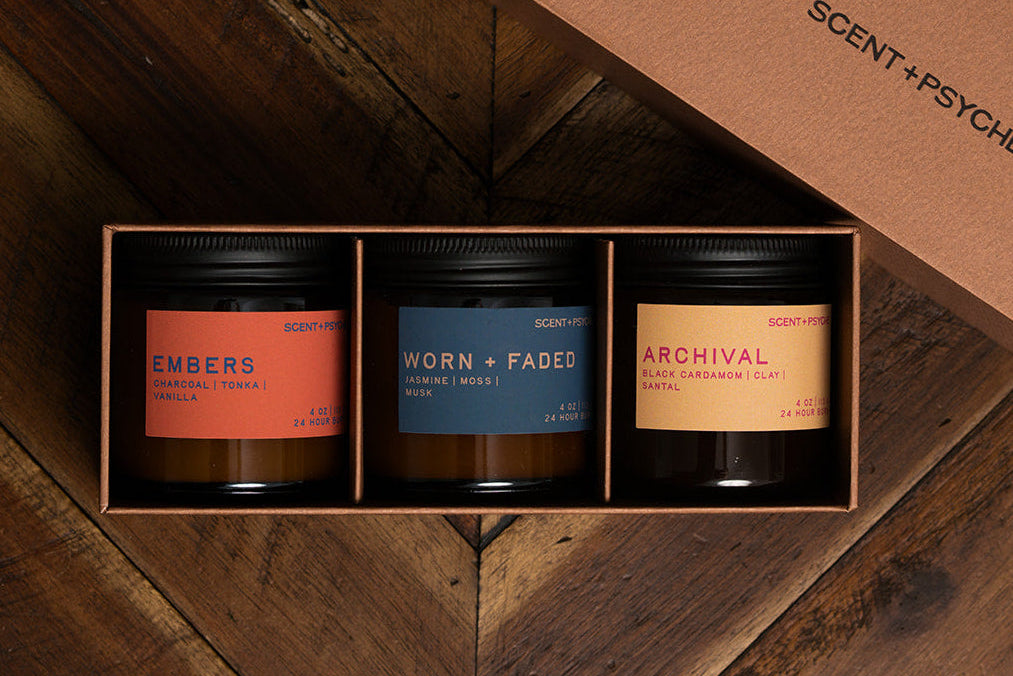 Scent + Psyche Warm + Cozy Discovery Bundle gift box with Embers, Worn + Faded, and Archival candles on dark wood
