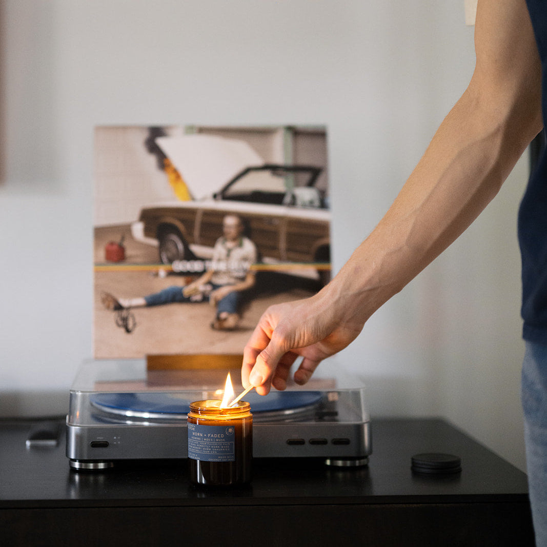 person lighting candle next to record player signature everyday scent — Scent & Psyche