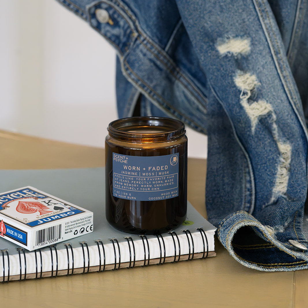 Worn and Faded candle styled with folded denim jeans, everyday signature scent — Scent & Psyche