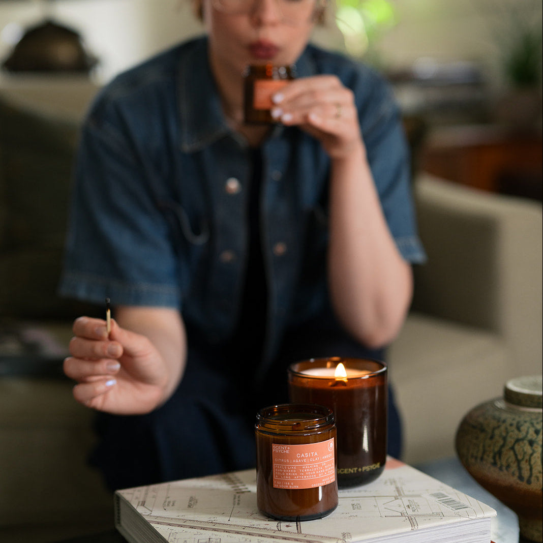 Person lighting a candle in a cozy living room setting