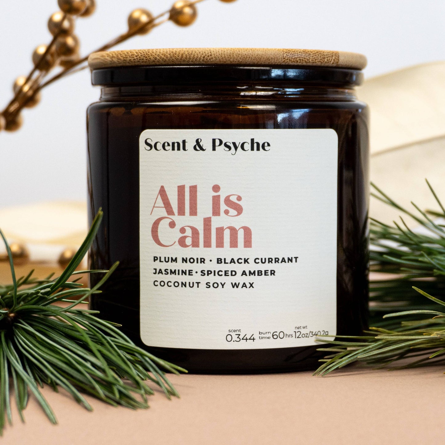 All is Calm Scented Candle in 12oz amber jar with wooden lid, featuring notes of plum noir, black currant, and spiced amber. Ideal for holiday decor.