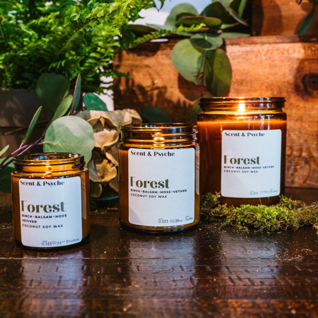 Collection of Forest Scented Candles in amber jars, available in multiple sizes. Infused with birch, balsam, and moss for a refreshing home fragrance.