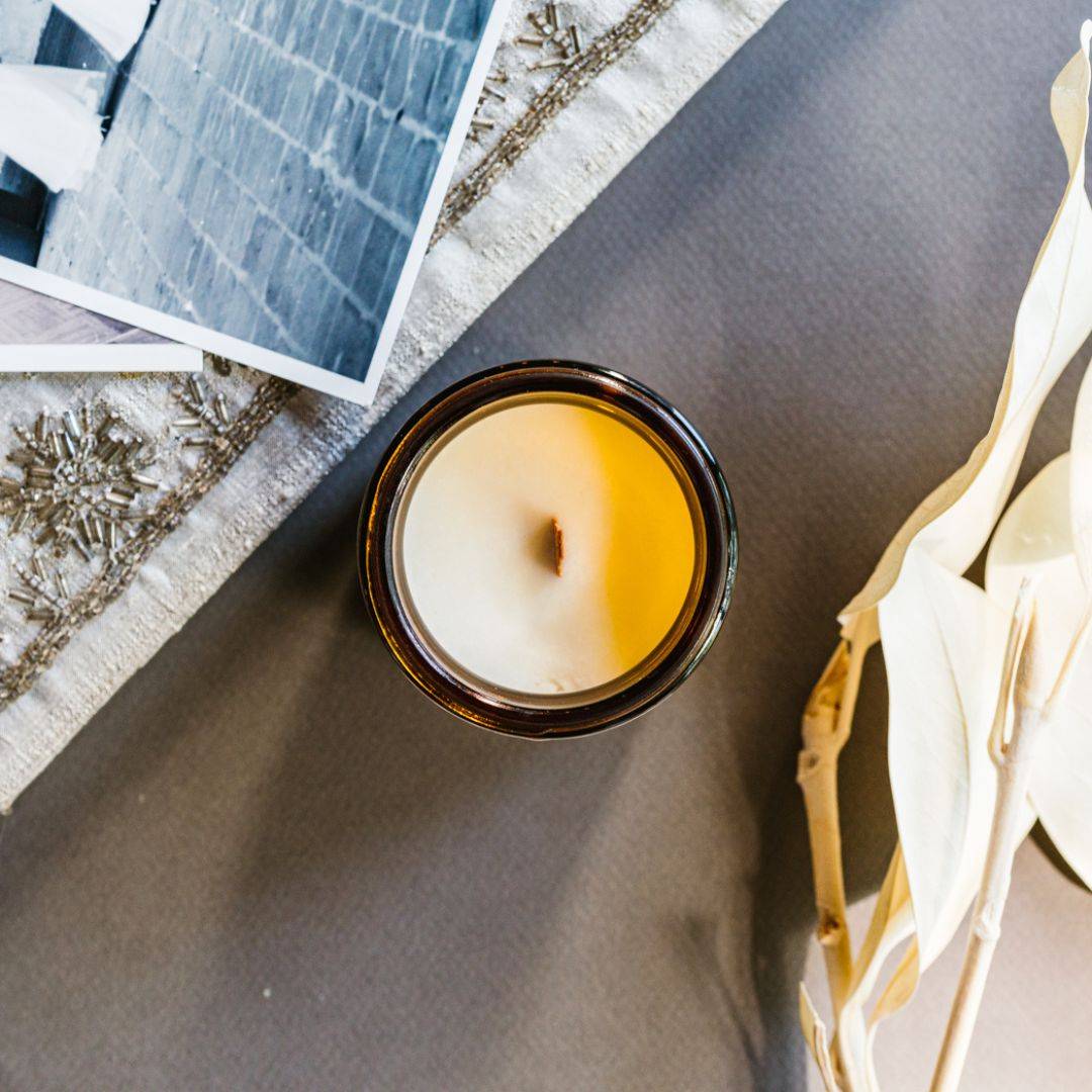 Top view of the Heirloom Scented Candle in a 4oz amber jar, showcasing a wooden wick and creamy coconut soy wax for a warm, aromatic experience.