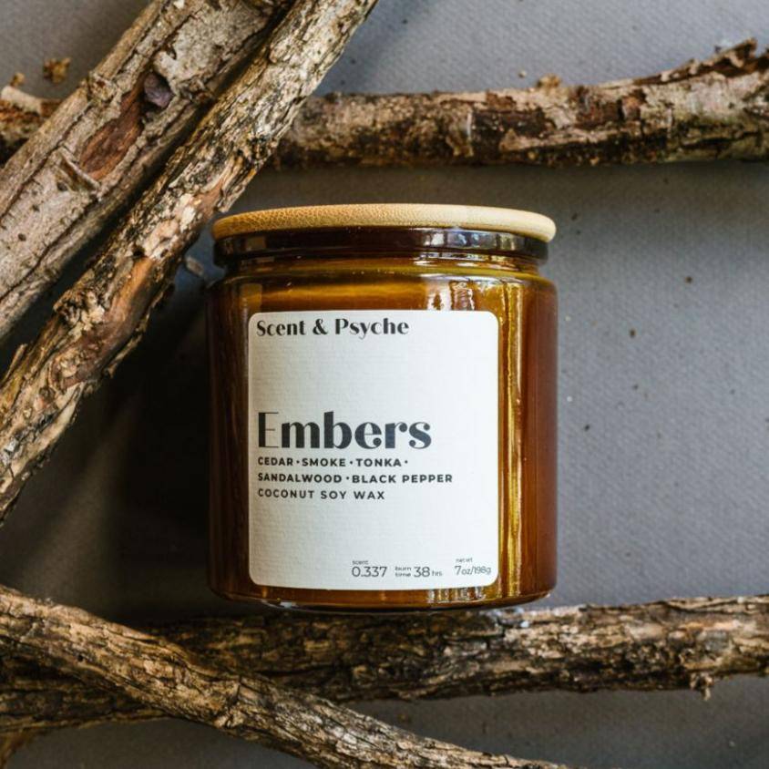 Embers Scented Candle in a 12oz amber jar with a wooden lid, featuring notes of cedar smoke, tonka, sandalwood, and black pepper. Perfect for cozy home ambiance.