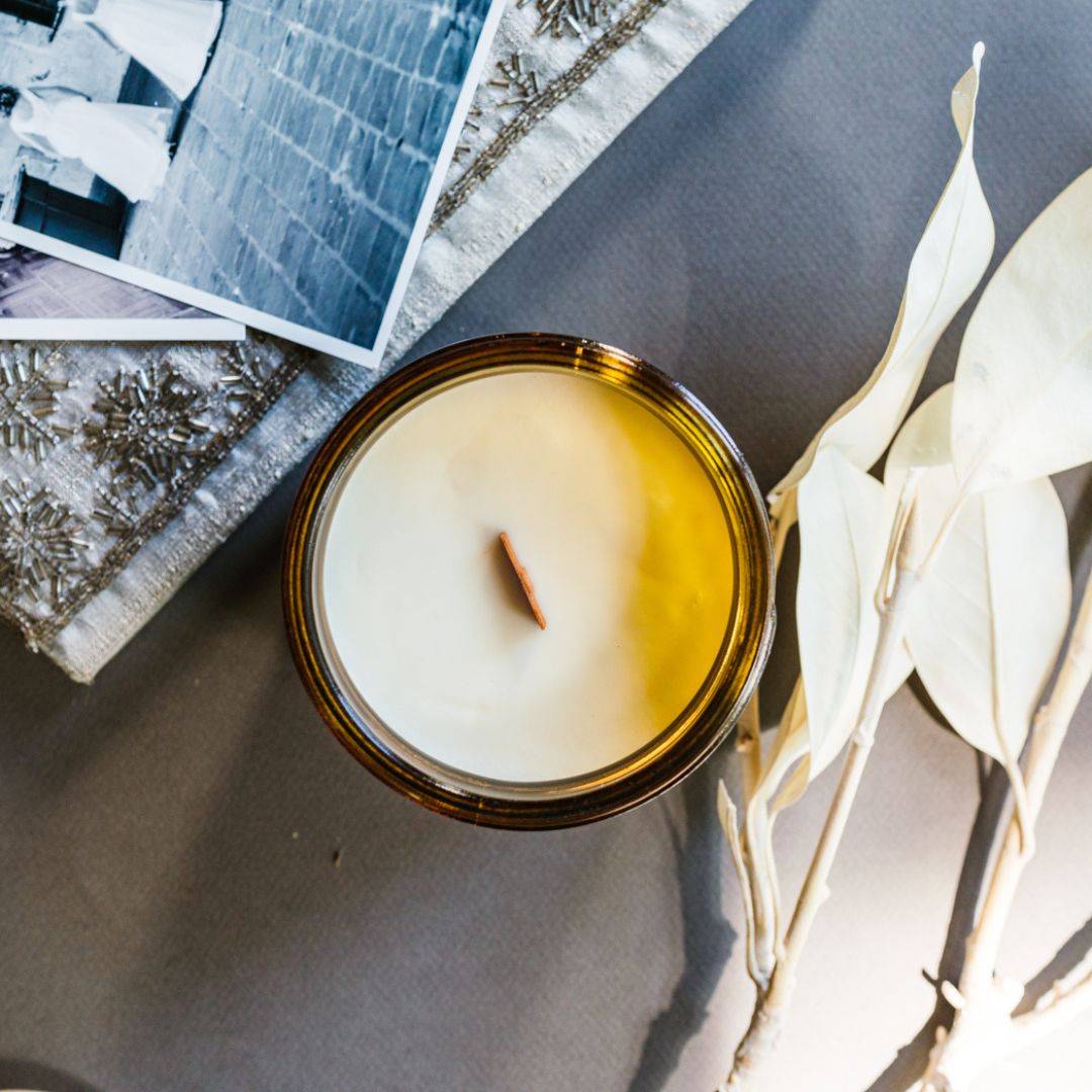 Top view of the Heirloom Scented Candle in a 15oz amber jar, showcasing a smooth coconut soy wax surface with a wooden wick. Elegant home fragrance addition.