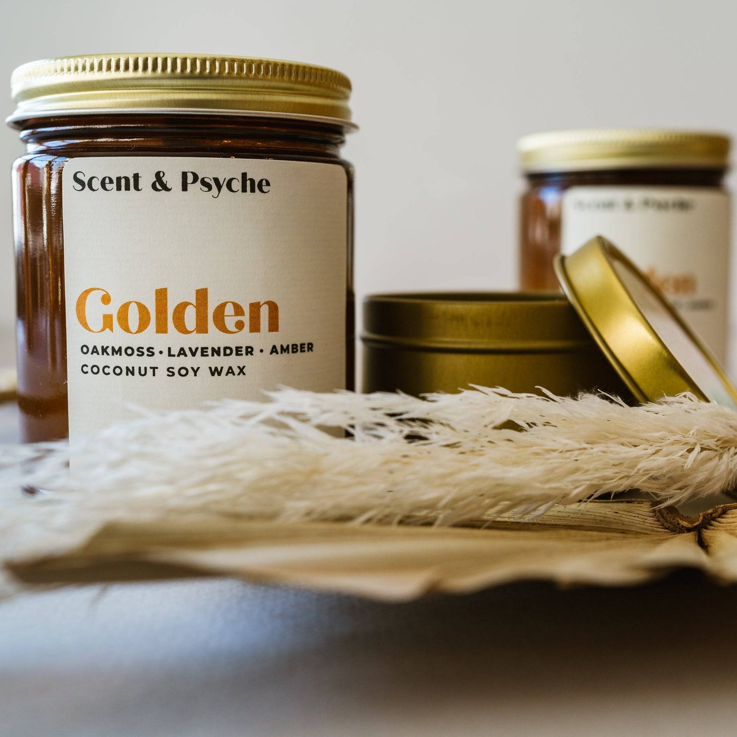 Golden Scented Candle in a 7oz amber jar with a minimalist label, surrounded by dried botanicals. Aesthetic home fragrance with coconut soy wax blend.