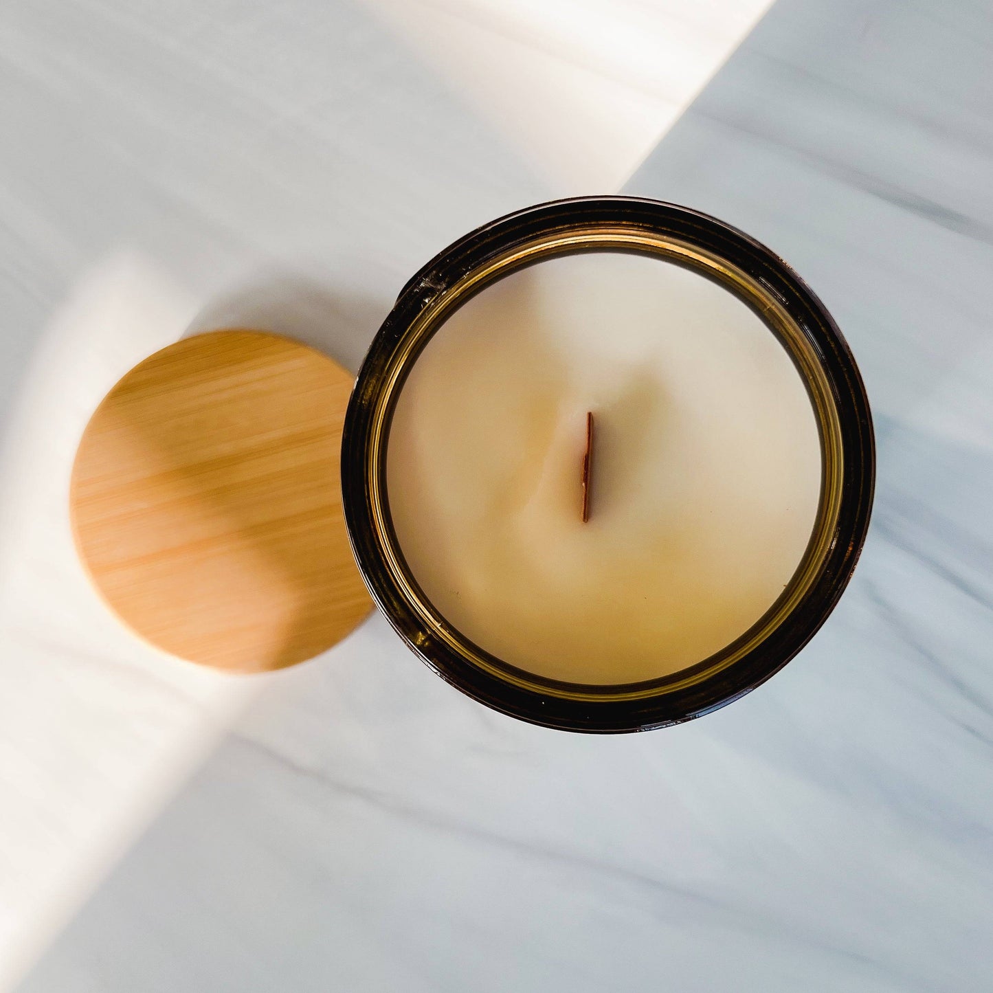 Top view of Barrel-Aged Scented Candle in a 12oz amber jar, showcasing a smooth coconut soy wax surface with a wooden wick and a bamboo lid.