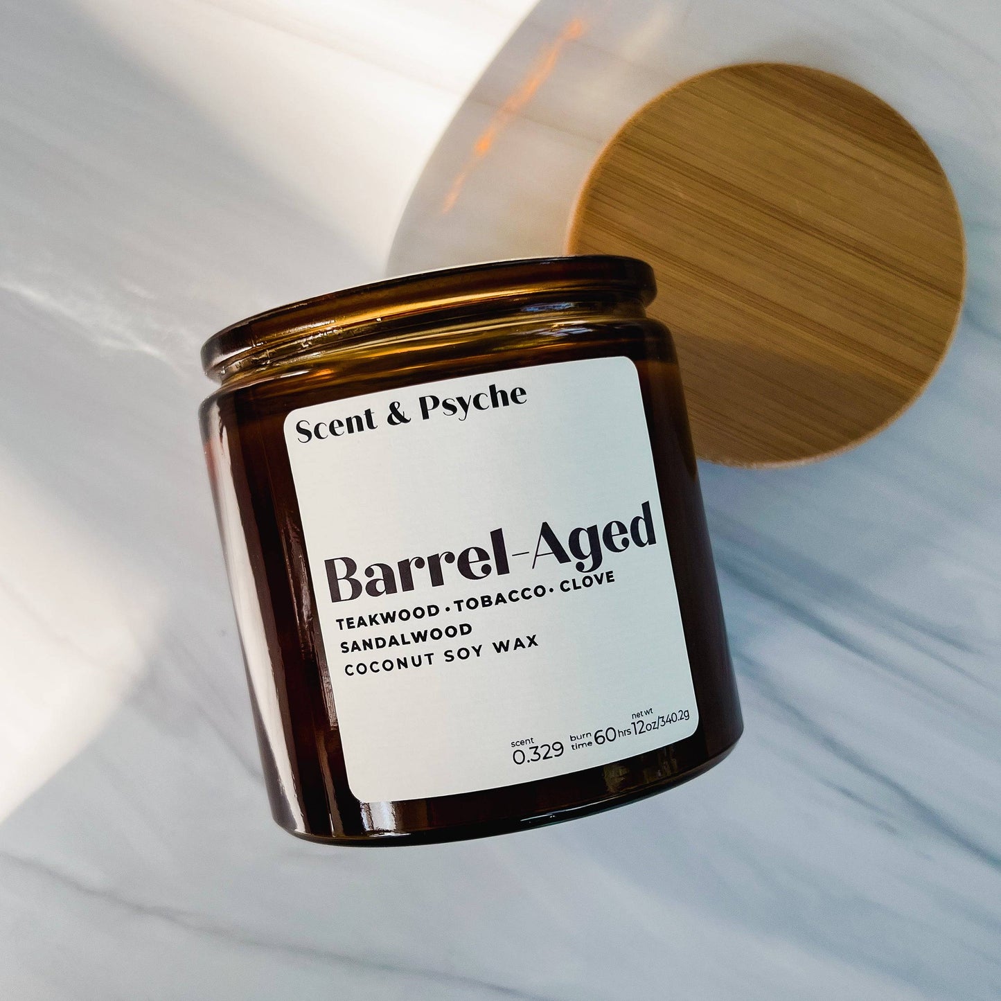 Barrel-Aged Scented Candle in a 12oz amber jar with a wooden lid. Features teakwood, tobacco, clove, sandalwood, and coconut soy wax blend.