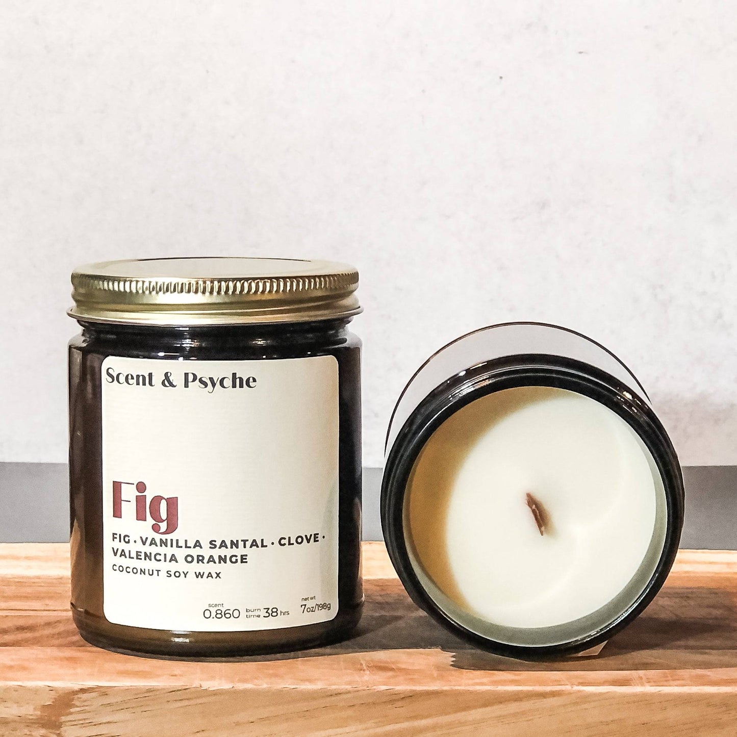 Amber jar Fig Scented Candle with a wooden wick, offering a blend of fig, vanilla santal, clove, and Valencia orange. Crafted from coconut soy wax for a clean burn.