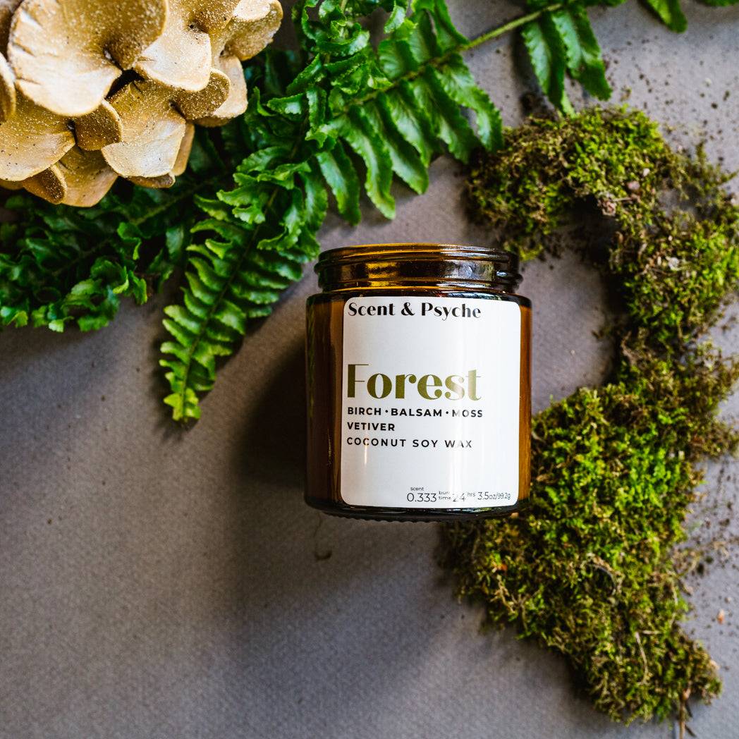Forest Scented Candle in a 4oz amber jar with birch, balsam, and moss fragrance. Perfect for a cozy home ambiance with natural decor elements.