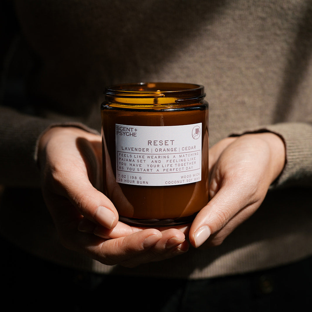 Person holding a candle labeled 'Reset' in a dimly lit setting