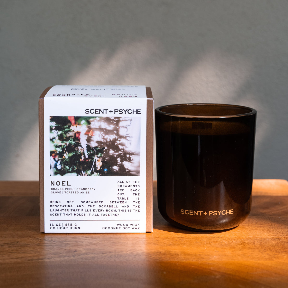 Noel Statement size candle next to its Scent + Psyche gift box in window light